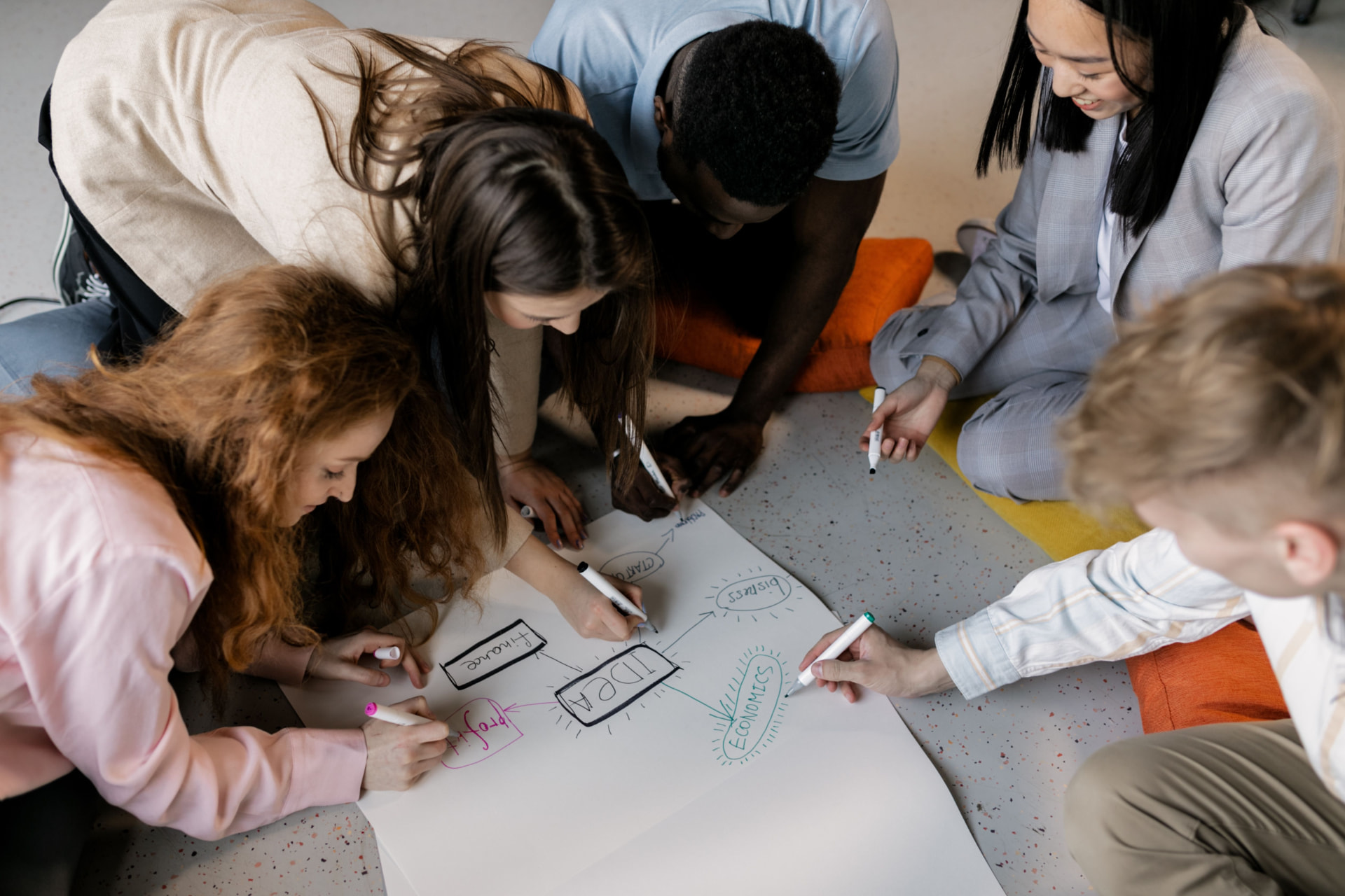 Equipo trabajando en conjunto sobre un gran papel, dibujando un mapa de ideas en un taller de innovación